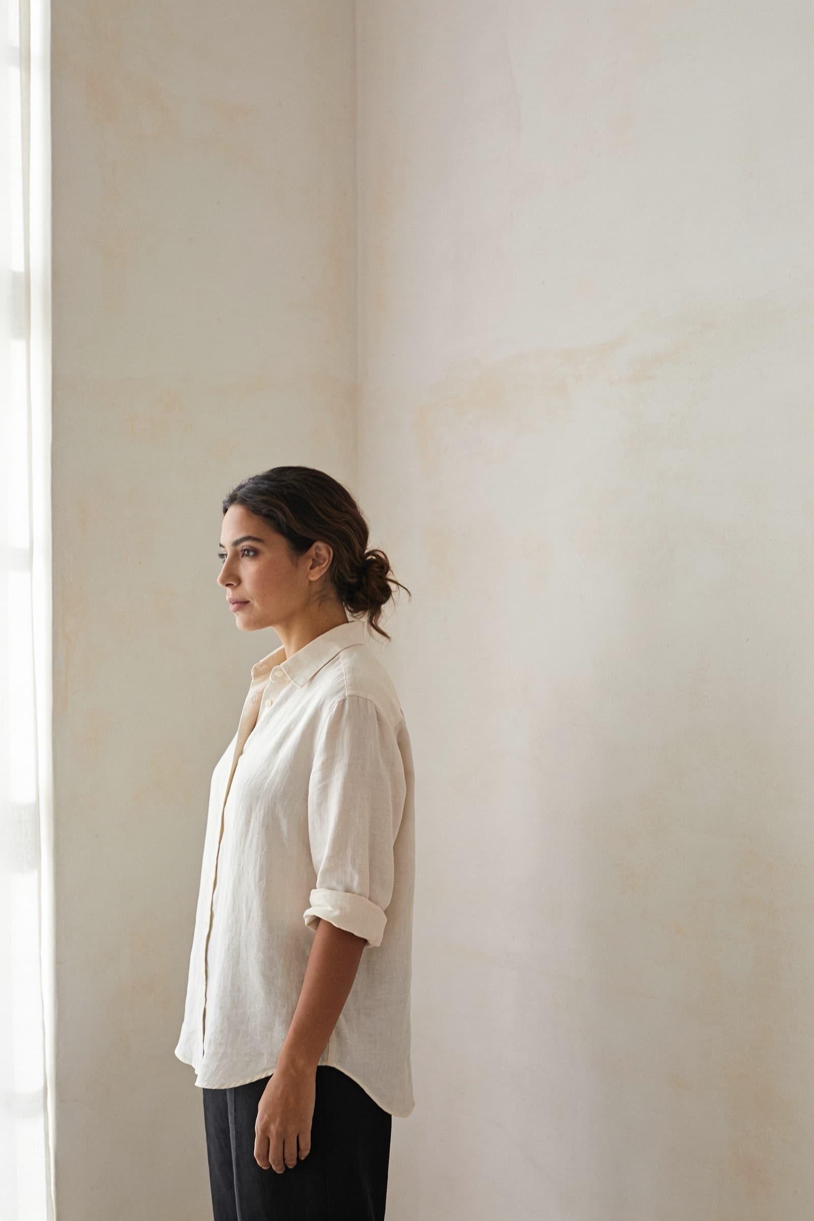 Mujer con camisa de popelina ivory con las mangas recogidas, de perfil